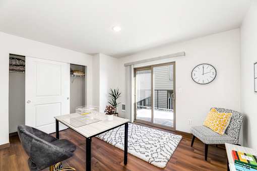 A white table with a glass top sits in the middle of a room with a grey chair and a white couch.