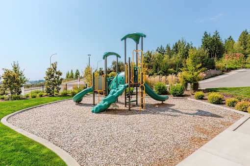 A playground with a green slide and yellow safety bars.