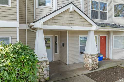 A house with a red door and a stone pillar in front of it.