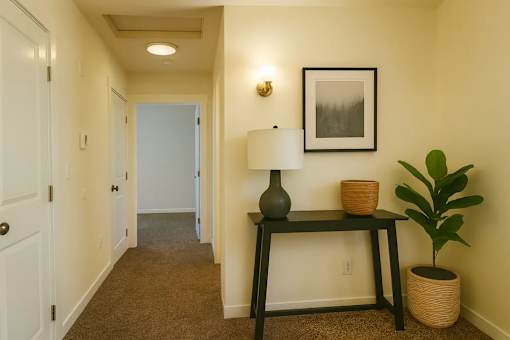 A hallway with a lamp and a plant on a table.