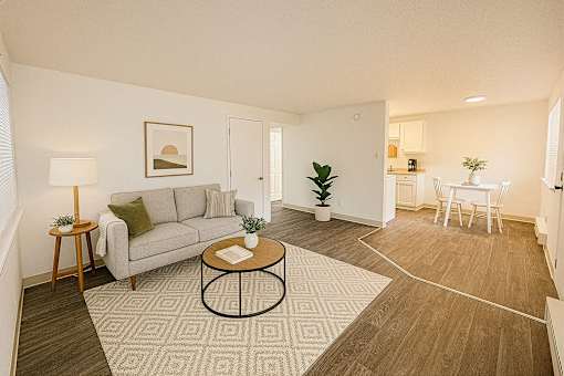 A living room with a grey couch, a coffee table, and a dining table with chairs.