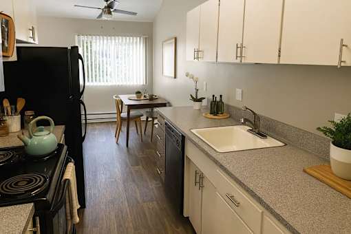 A kitchen with a black refrigerator and wooden floors.