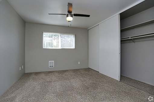 A room with a ceiling fan and a window with blinds.