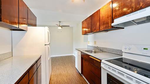 A kitchen with white appliances and wooden cabinets.