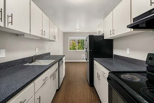 A kitchen with black appliances and white cabinets.