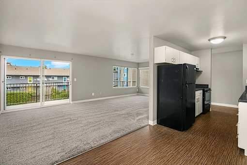 A black refrigerator sits in a kitchen next to a window.