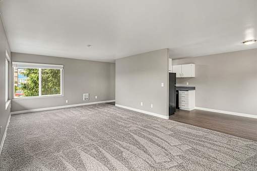 A spacious room with a grey carpet and a window.