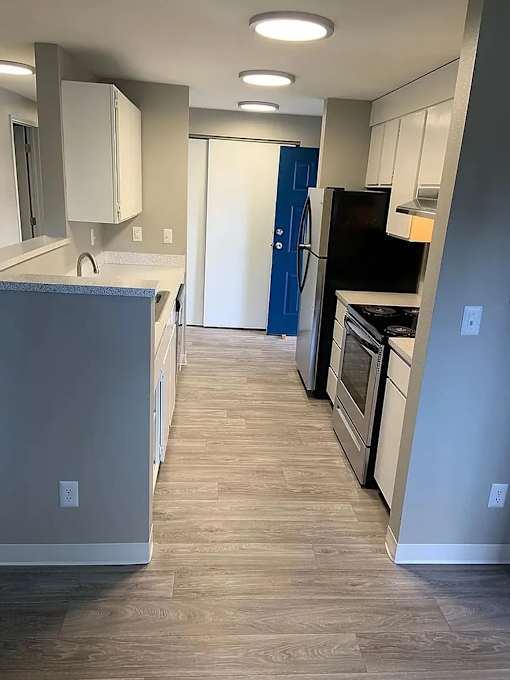 A kitchen with a blue door and wooden floors.