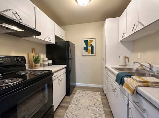 A kitchen with black and white appliances and a fridge with a picture hanging on the wall.