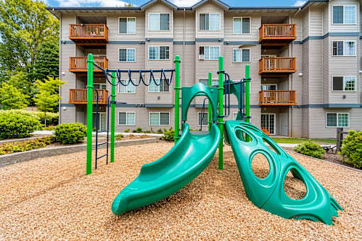 A green playground slide in front of a building.