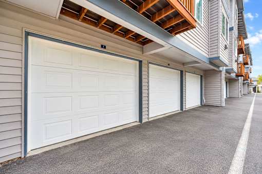 A row of white garage doors in front of a building.