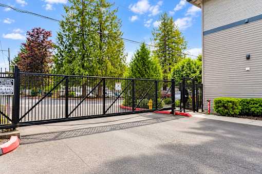 A black metal gate with a sign that reads "No Trespassing" is blocking the entrance to a driveway.