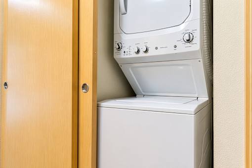 A white washing machine is in a wooden cabinet.