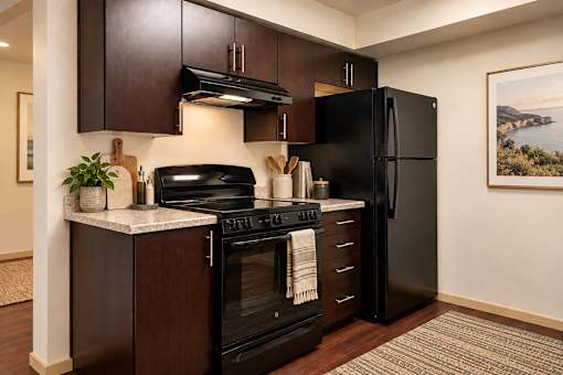 A black refrigerator is in a kitchen with a stove and oven.
