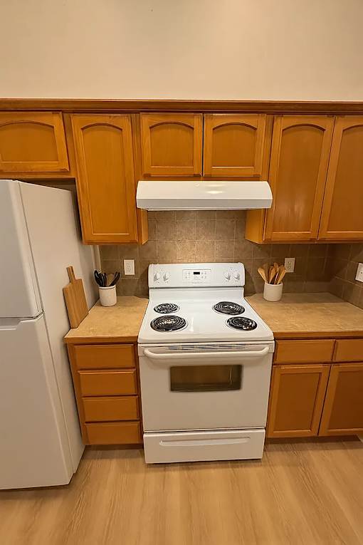 A white stove in a kitchen with wooden cabinets.