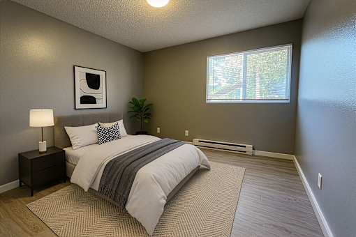 A bedroom with a bed, nightstand, and window.
