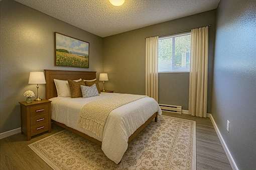 A bedroom with a bed, nightstand, and a painting on the wall.