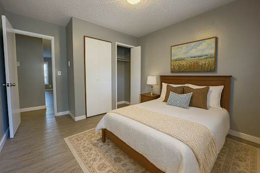 A bedroom with a bed, two pillows, and a painting on the wall.