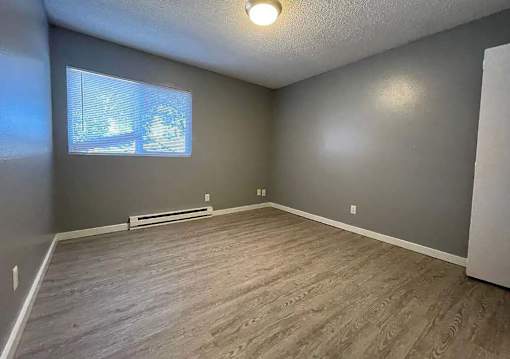 A room with a window and a wooden floor.