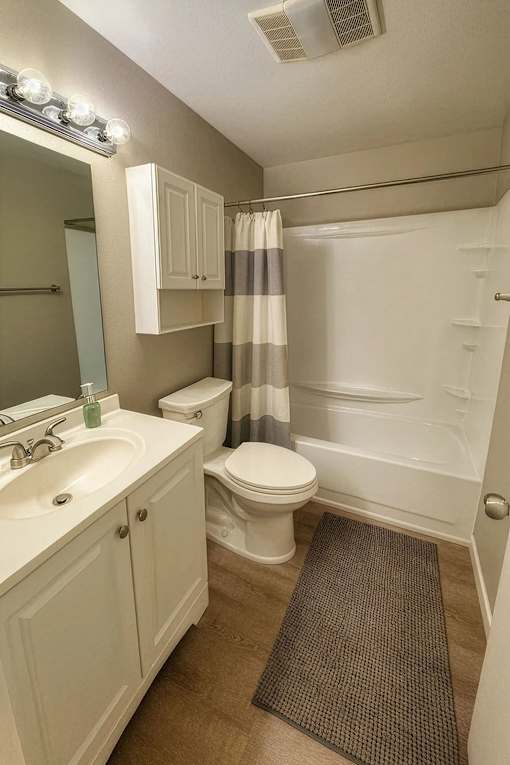 A small white bathroom with a toilet, sink, and shower.