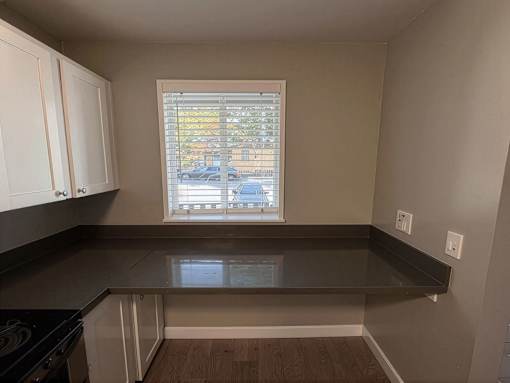A kitchen with a black countertop and white cabinets.