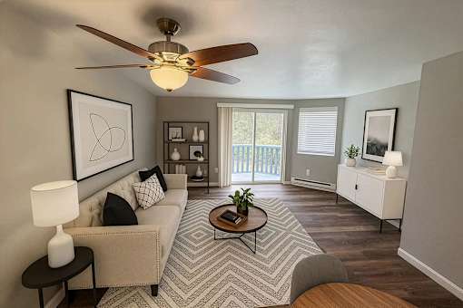A living room with a beige couch, a coffee table, and a ceiling fan.