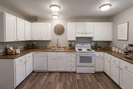 A kitchen with white cabinets and a wooden floor.