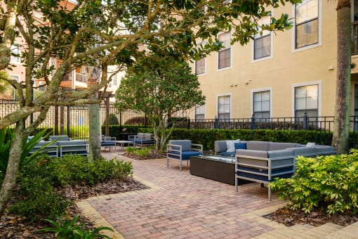 a courtyard with couches and chairs in front of an apartment building