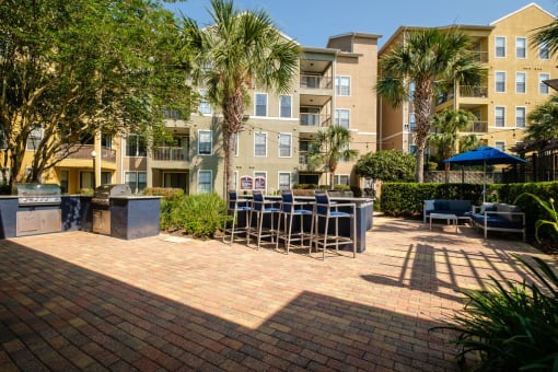 a patio with tables and chairs in front of an apartment building