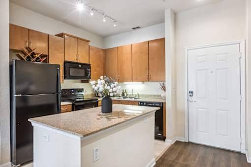 A kitchen with a black refrigerator and white cabinets.