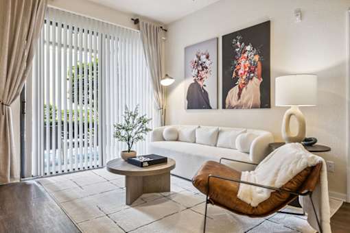 A living room with a white couch, a brown leather chair, and two paintings on the wall.
