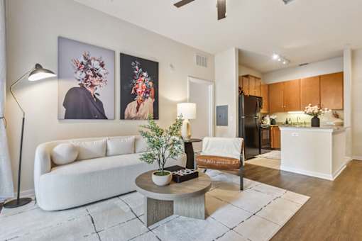 A living room with a white couch, a coffee table, and two abstract paintings on the wall.