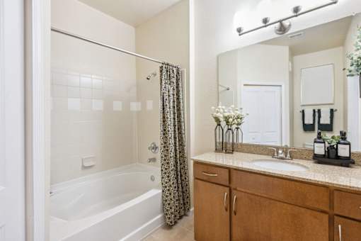 A bathroom with a white tub, a sink, and a mirror.