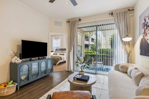 A living room with a television, sofa, and sliding glass doors.