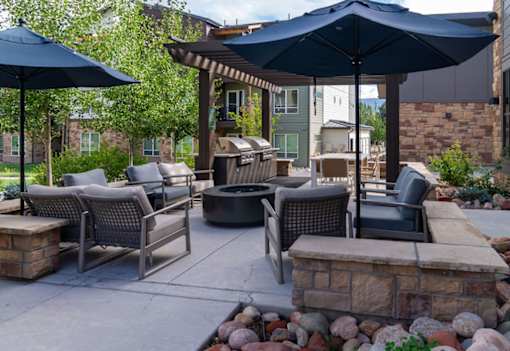A patio with a fire pit and chairs.