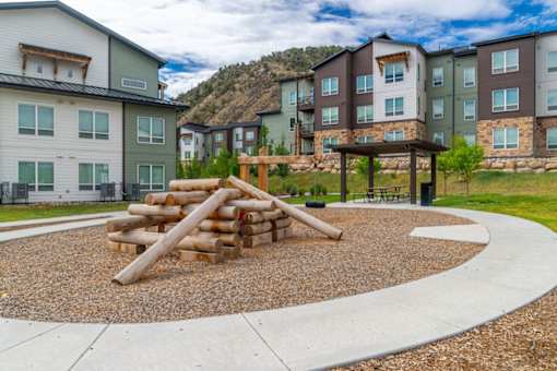 A playground area with a pile of logs in the middle of a gravel area. Eagle Colorado