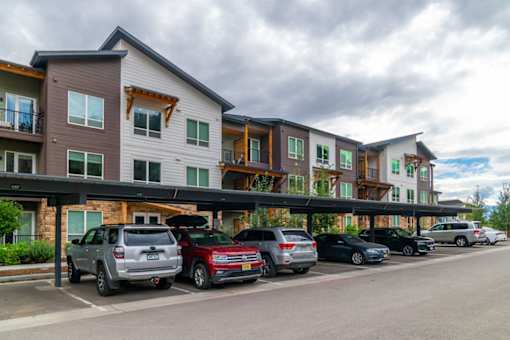 A row of cars are parked in front of a building.