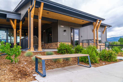 A modern house with a wooden porch and a bench in front.