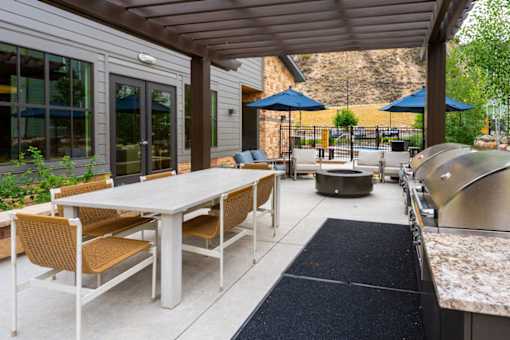 A patio with a table and chairs and a grill.