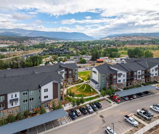 A view of a parking lot with cars and apartment buildings.