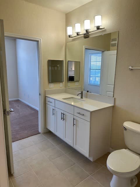 A bathroom with a toilet, sink, and mirror.