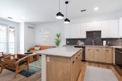 an open kitchen and living room with a marble counter top