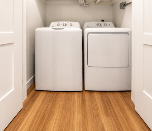 Two white front loading washing machines in a laundry room.