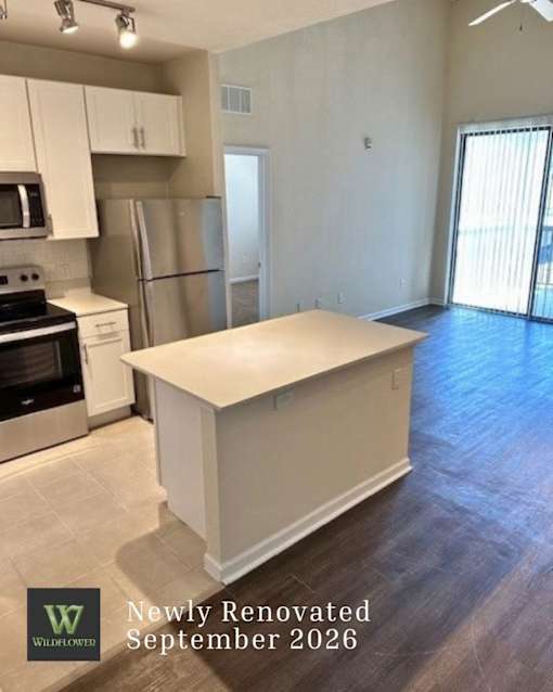 A newly renovated kitchen with a white island in the middle.