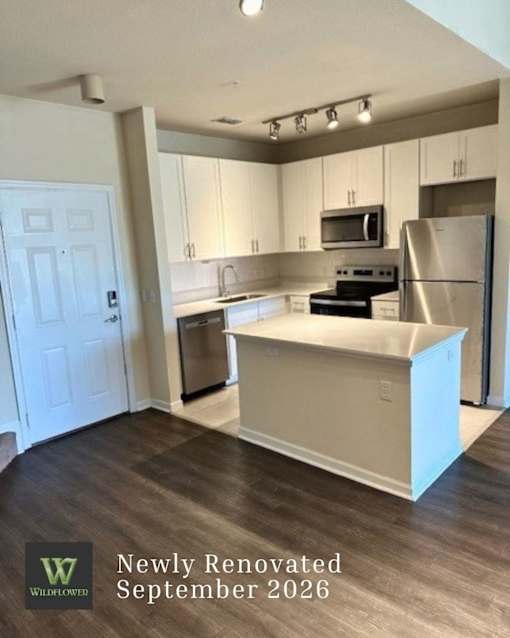 A newly renovated kitchen with a white island and stainless steel appliances.