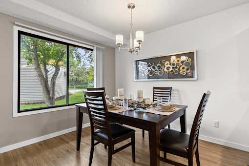 A dining room with a table set for two and a chandelier.