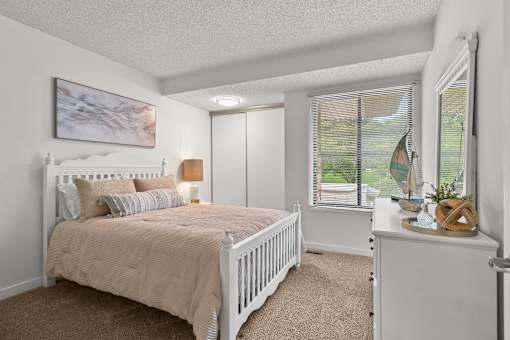 A bedroom with a large bed and a window with blinds.