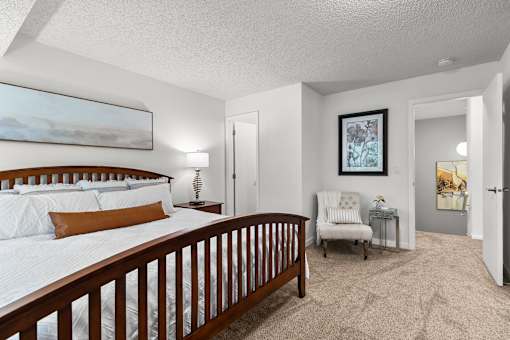 A bedroom with a large bed and a chair in it.