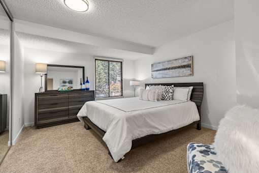 A bedroom with a bed, nightstand, and chair.