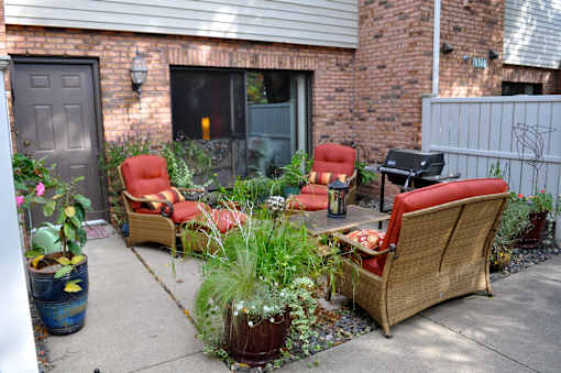 A patio with a wicker sofa and chairs surrounded by plants.